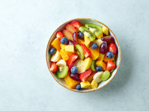 чаша с салатом из свежих фруктов на кухонном столе, вид сверху - Фото, изображение
