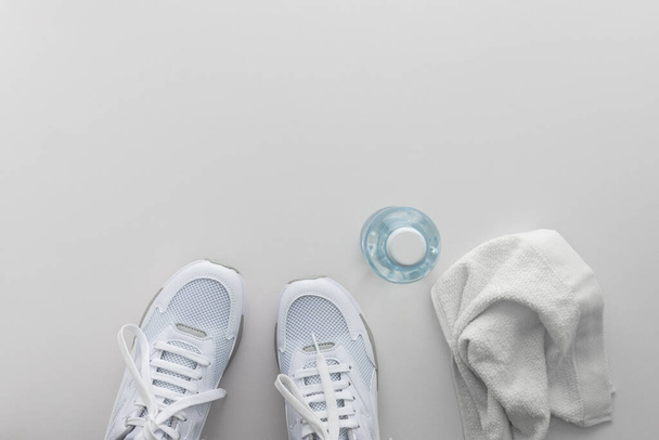 Sneakers sportive bianche con bottiglia d'acqua e asciugamano su sfondo bianco, fare sport e allenamento in sala, stile di vita sano, vista dall'alto, spazio copia - Foto, immagini