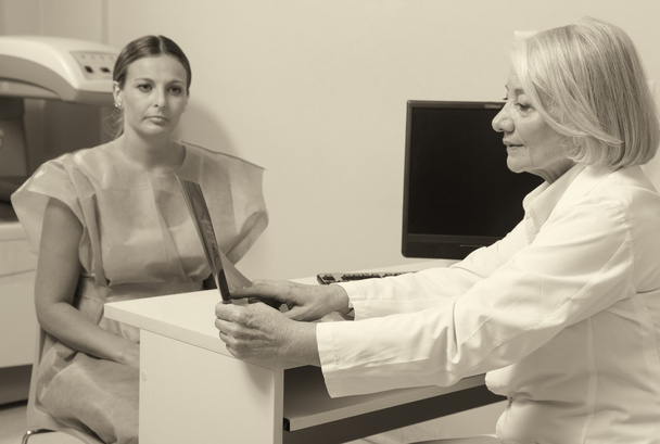 Worried senior female doctor analyzing medical x-ray with her 40 - Fotografie, Obrázek