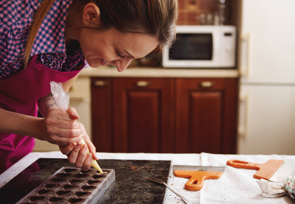 Усміхнений шоколатьє, насолоджуючись приготуванням розкішних шоколадних пралінів ручної роботи на домашній кухні для святкування Всесвітнього дня шоколаду
 - Фото, зображення