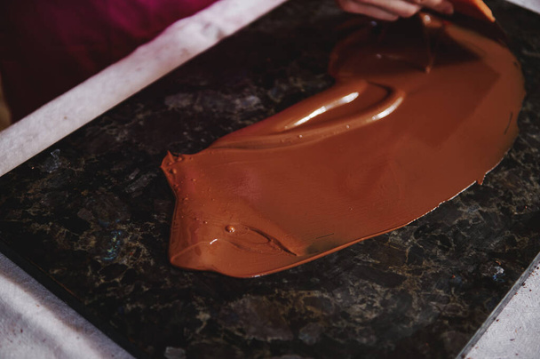 High angle view of tempering chocolate mass on a dark marble surface - Photo, Image