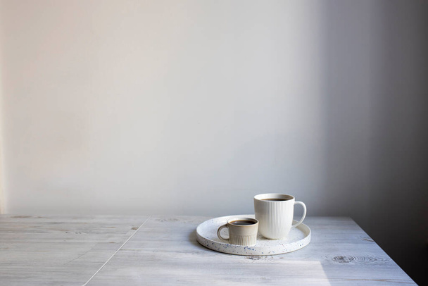 Minimalist İskandinav tarzı. Masadaki tepside iki kişi için farklı boyutlarda iki fincan kahve.. - Fotoğraf, Görsel