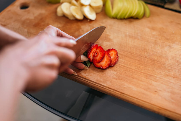 Close up shot woman standing kitchen hold hand cut chopping red strawberry products fruits vegetables wooden cutting board. Lady preparing breakfast lunch, want cook healthy food, copyspace. - Photo, image