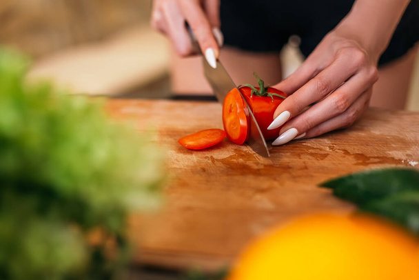 Close up shot woman standing kitchen hold hand cut chopping red tomato products fruits vegetables wooden cutting board. Lady preparing breakfast lunch, want cook healthy food, copyspace. - Fotoğraf, Görsel