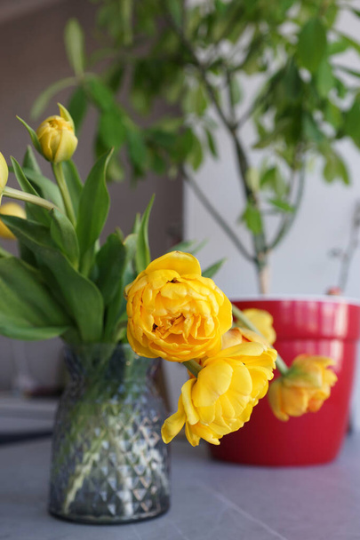 灰色のテーブルの上の花瓶に黄色のチューリップの花束 - 写真・画像
