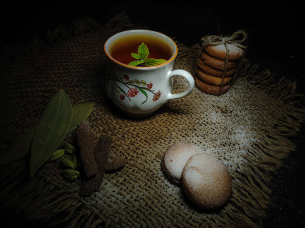 Closeup of Hot Freshly brewed Tea and Homebaked Wheat Biscuits or Cookies flavoured with Cardamon, Cinnamon Roll, Bayleaf with copy space for inscription. Food Photography. Masala chai. Hot beverage. Pastry. Bakery. - Photo, Image