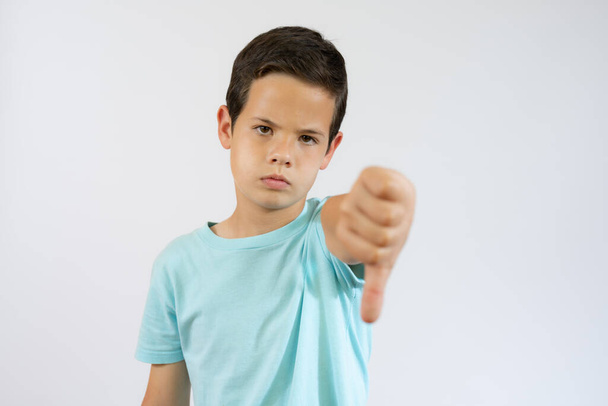 Young little caucasian kid over white background looking unhappy and angry showing rejection and negative with thumb down gesture. Bad expression. - Foto, immagini