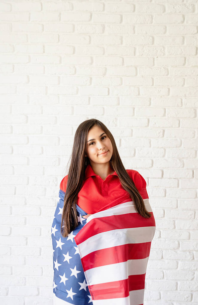 Independence day of the USA. Happy July 4th. Young smiling woman with national flag of the USA. - Photo, image