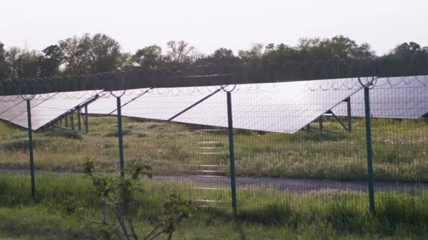 Солнечные панели ограждены оградой из колючей проволоки. Солнечные батареи. 4K - Кадры, видео