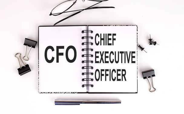 Notitieboekje met CFO of Chief Financial Officer op tafel met kantoorgereedschap - Foto, afbeelding