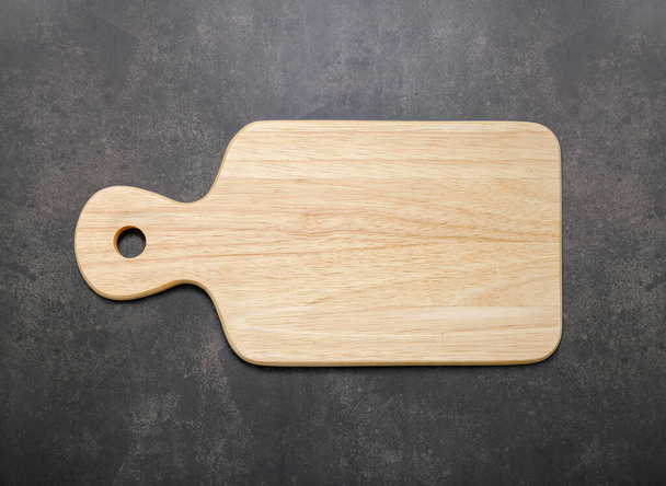 Empty vintage wooden cutting board set up on dark concrete background with copy space. - Photo, Image