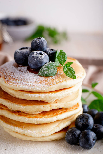 Homemade pancakes with blueberries and powdered sugar on the table close-up vertical photo - Foto, afbeelding