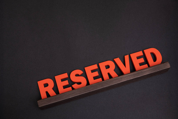 Service reserve at restaurant table. Large red plaque sign with wooden letters. Top view. Black background. - Photo, Image