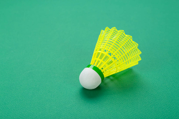 Badminton ball or shuttlecock on green background.   Popular indoor sport concept.  - Photo, Image