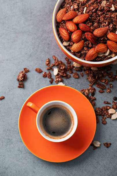 Orange Kaffeetasse mit Mandel-Müsli auf steinigem Hintergrund. gesundes Frühstück. Ansicht von oben. - Foto, Bild