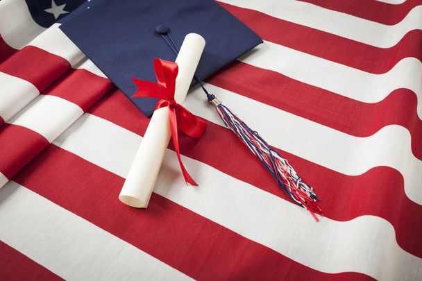 Шапка и диплом об окончании учебы на американском флаге
 - Фото, изображение