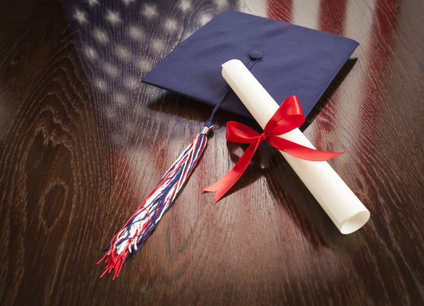 Cap de Graduação e Dipoma na Mesa com Reflexão da Bandeira Americana
 - Foto, Imagem