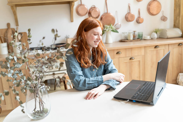 Online video call using laptop at kitchen. Red haired white woman having online conference smiling enjoying conversation. Long distance relationship. Stay home freelance remote work from home. Blue - Foto, imagen