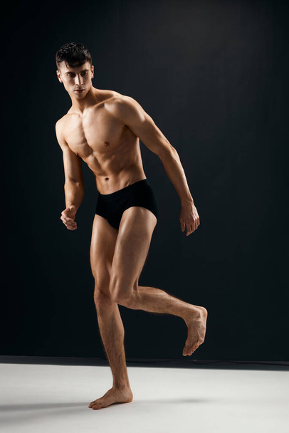 mies musta pikkuhousut alasti lihaksikas elin poseeraa tummaa taustaa vasten - Valokuva, kuva