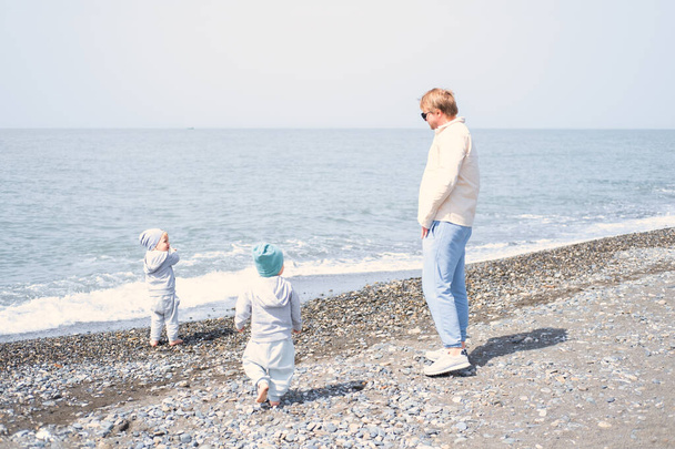 père et enfants deux garçons jumeaux jouer avoir du plaisir sur la plage au printemps ou en automne. - Photo, image