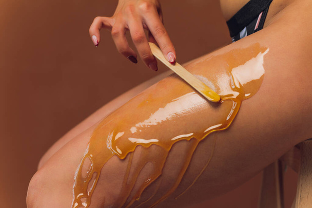Hair removal with sugar. In the office of a cosmetologist. - Fotoğraf, Görsel