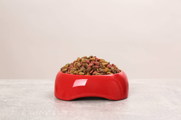 Dry cat food in red pet bowl on grey surface - Fotografie, Obrázek
