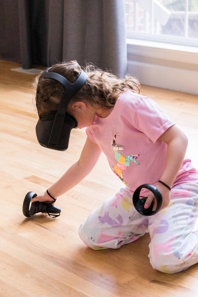 klein meisje spelen virtual reality spel in de woonkamer, - Foto, afbeelding