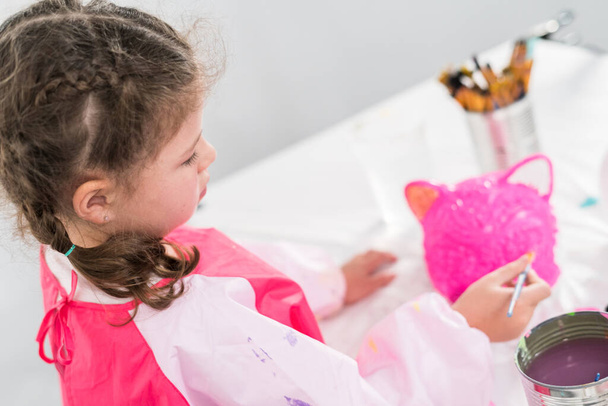 Маленька дівчинка малює гарбуз на Хеллоуїн з акриловою фарбою
. - Фото, зображення