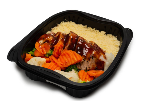 Ready food in a container. Stewed chicken in teriyaki sauce, stewed carrot, cabbage and porridge. Isolated on a white background.  - Фото, зображення