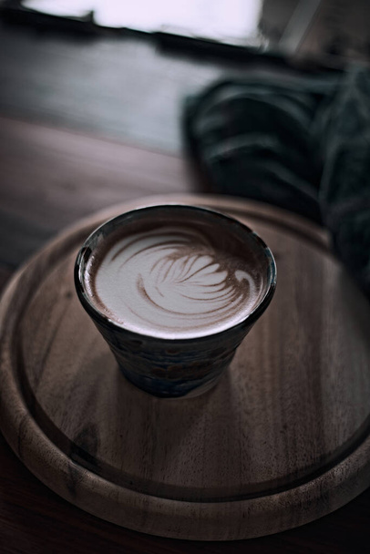 Selectieve focus cup van hete latte art koffie op houten tafel, focus op witte foa - Foto, afbeelding
