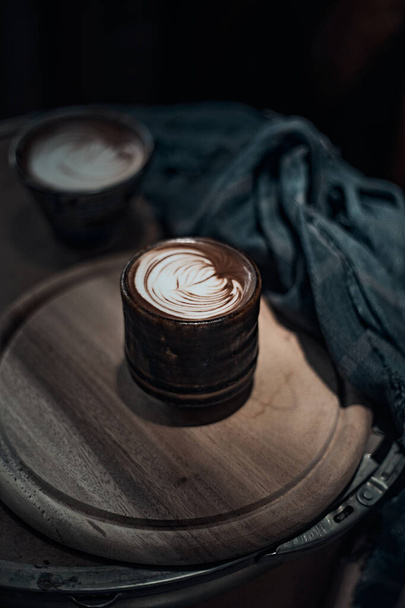 Copo de foco seletivo de café de arte de latte quente na mesa de madeira, foco no foa branco - Foto, Imagem