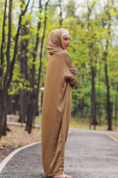 Islamic beautiful woman in a Muslim dress standing on a summer park street background forest autumn trees.world hijab day. - Foto, Imagem