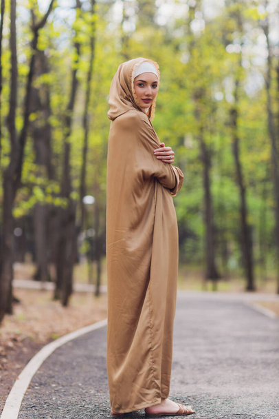 Iszlám gyönyörű nő egy muszlim ruhát áll egy nyári park utcai háttér erdő ősszel fák.világ hidzsáb nap. - Fotó, kép