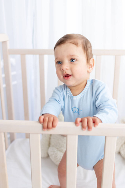 Bir çocuk odasındaki beşikte büyük mavi gözlü bir erkek bebek portresi. - Fotoğraf, Görsel