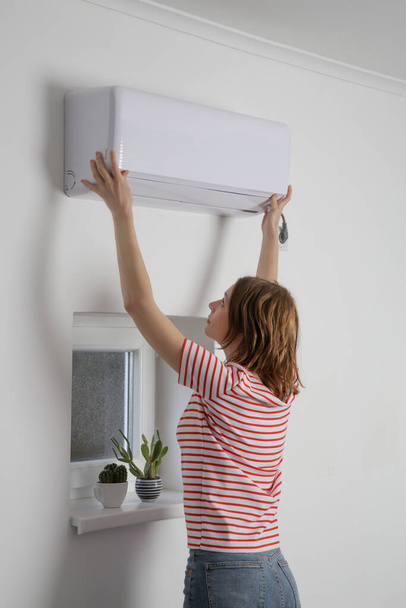 Vrouw repareert airconditioner thuis. - Foto, afbeelding