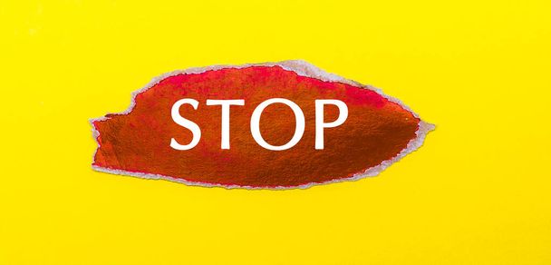 Su uno sfondo giallo, un foglio di carta rossa con la parola STOP - Foto, immagini