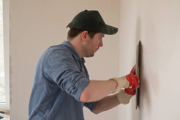 Чоловік з шпаклівкою ножем ремонтує стіну в квартирі
. - Фото, зображення