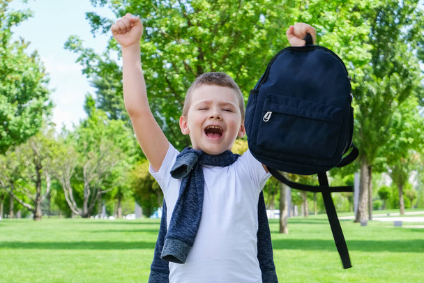 Happy schoolboy with a backpack in his hands on the street on the way to school. Back to school. - Фото, изображение