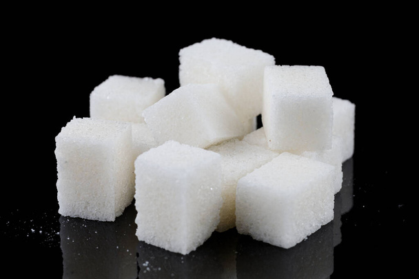Cubos de açúcar branco sobre um fundo preto - Foto, Imagem