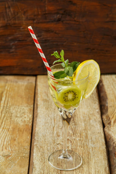 Cocktail with kiwi mint and lemon in a glass on a wooden table. copy space. Vertical photo - Фото, зображення