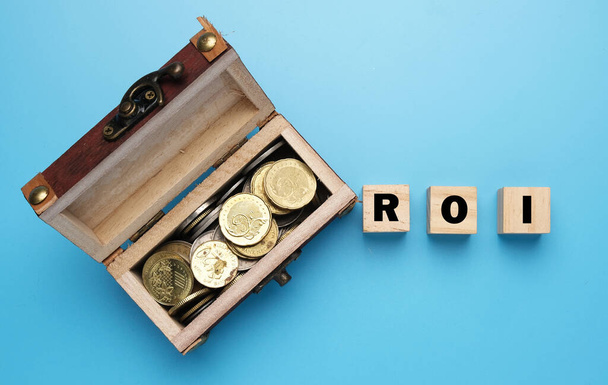 Ein Bild der Goldkiste mit ROI-Wort auf Holzblock. ROI ist Return on Investment. - Foto, Bild