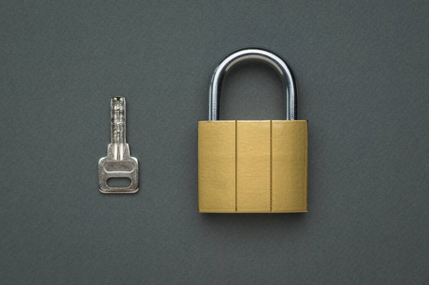 Closed classic lock and key on a gray background. The concept of protection and security. Flat lay. - Φωτογραφία, εικόνα