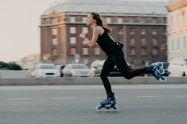 Frau fährt auf Rollern bewegt sich sehr schnell in aktiver Kleidung genießt Inlineskaten in Action-Posen an einem urbanen Ort, wo Extremsport betrieben wird. Aktives Lifestyle-Konzept - Foto, Bild
