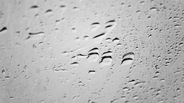 Gotas de agua de lluvia sobre fondo macro ventana de superficie de vidrio. Lluvioso clima deprimente y cielos grises fondo de pantalla - Foto, imagen