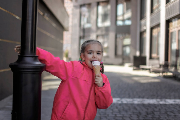 Hezká dívka jíst zmrzlinu na ulici nad městským pozadím, legrační sladkosti dítě, mimo životní styl - Fotografie, Obrázek