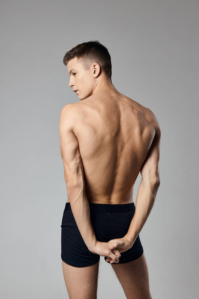 schöner Mann mit aufgepumpten Armmuskeln nackter Rücken graues Hintergrundmodell - Foto, Bild