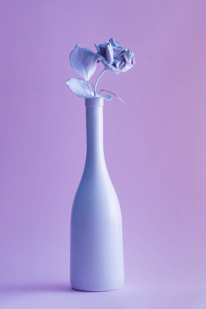 Biała butelka szampana i róża z kolorowymi ultrafioletowymi światłami holograficznymi. Koncepcja kreatywności. - Zdjęcie, obraz