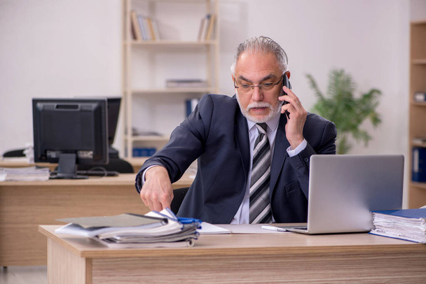 Aged businessman employee sitting in the office - 写真・画像