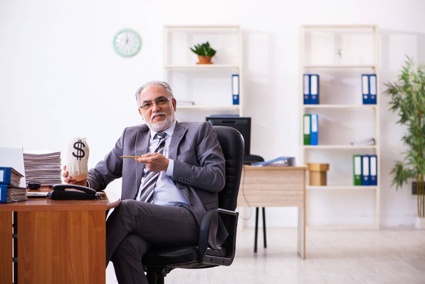 Старий чоловік бізнесмен працівник тримає монібаг в офісі
 - Фото, зображення