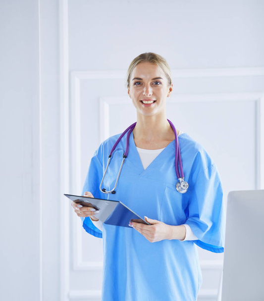 Smiling female doctor with a folder in uniform standing - Foto, afbeelding